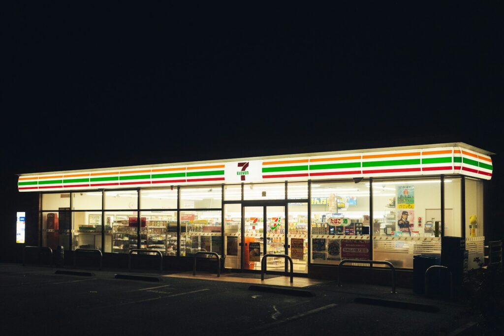 A brightly lit 7-Eleven convenience store at night in Japan