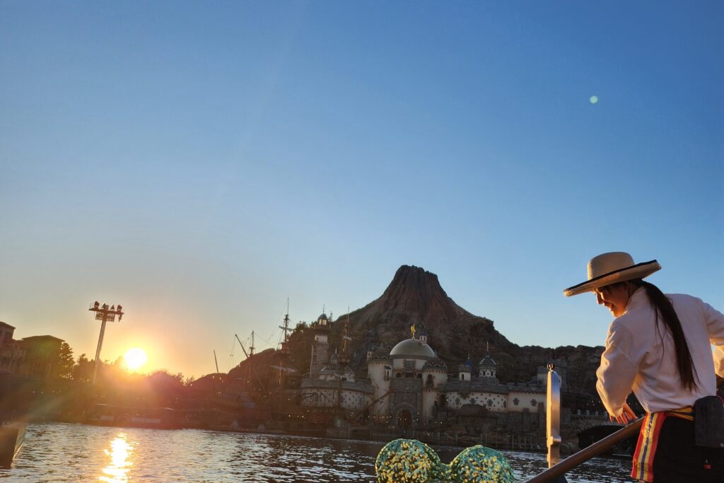 A gondola ride at Tokyo DisneySea at sunset, with Mount Prometheus and the Mediterranean Harbor skyline in the background.
