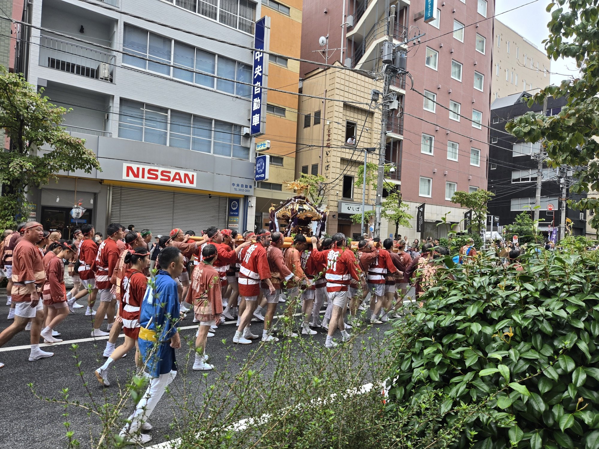 Festival participants carrying a mikoshi through a Tokyo street during a summer festival.