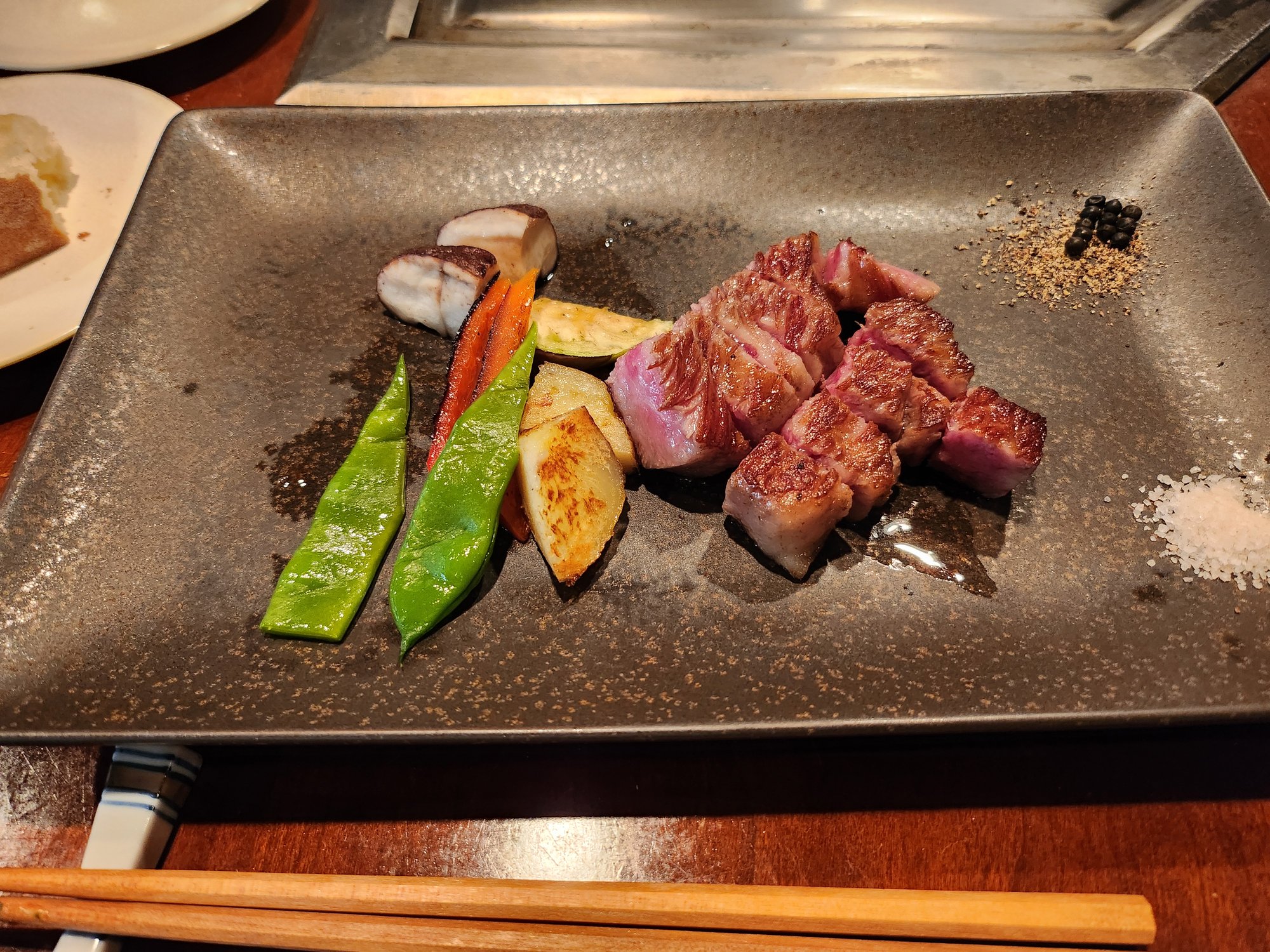 Grilled wagyu beef cubes and vegetables on a teppanyaki plate.
