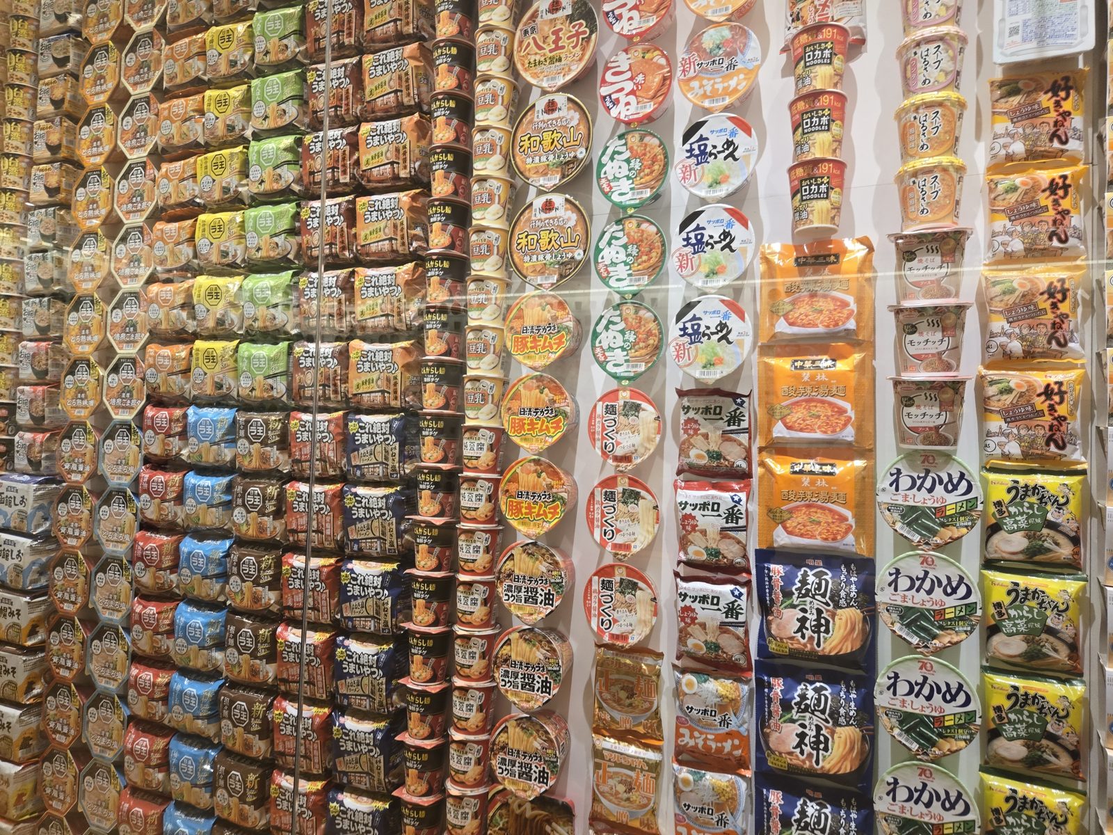 A wall covered with rows of instant noodle cups and packets on display at the Cup Noodles Museum Yokohama.