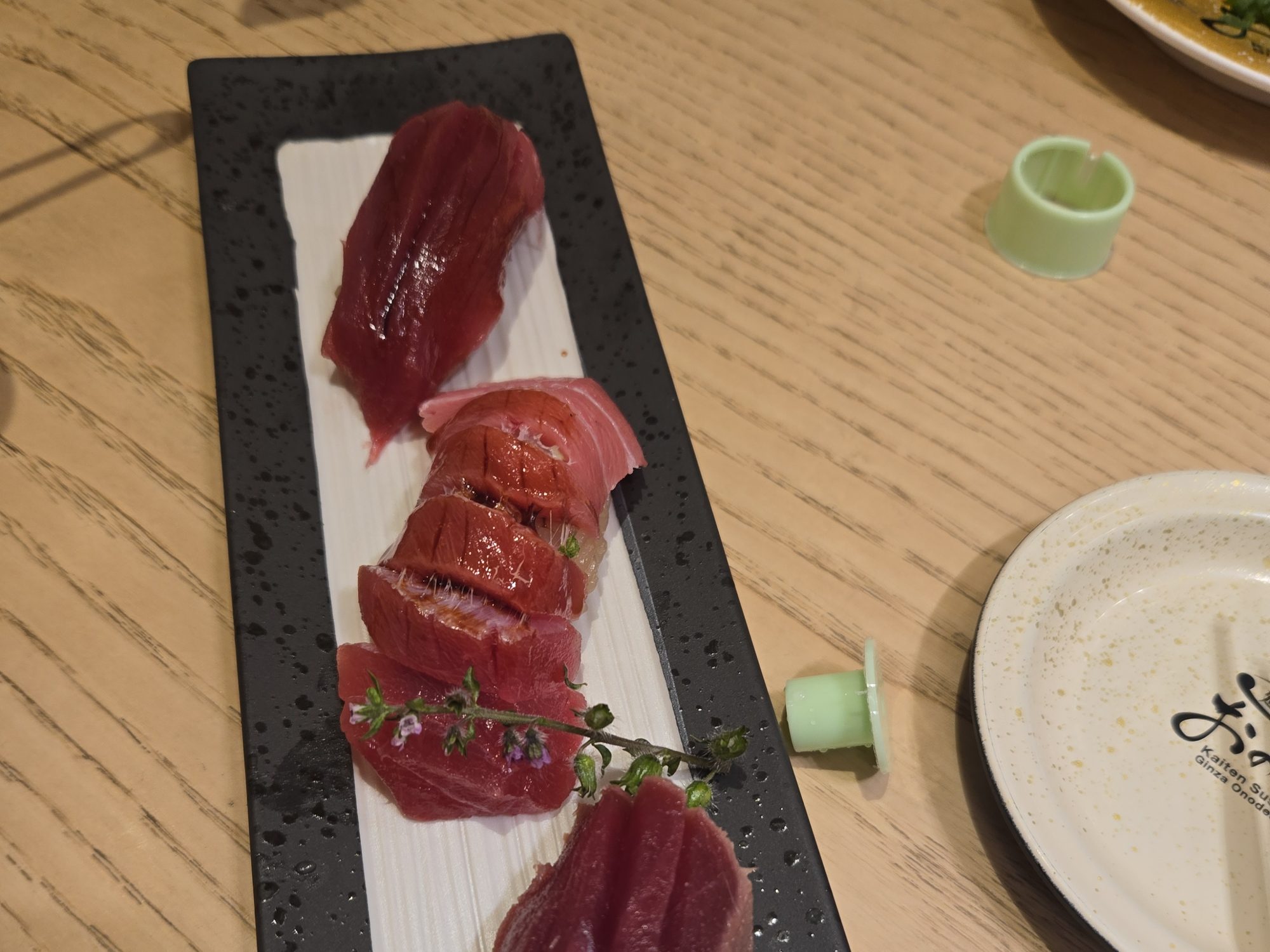 A long plate with three cuts of tuna nigiri at Kaiten Sushi Ginza Onodera.