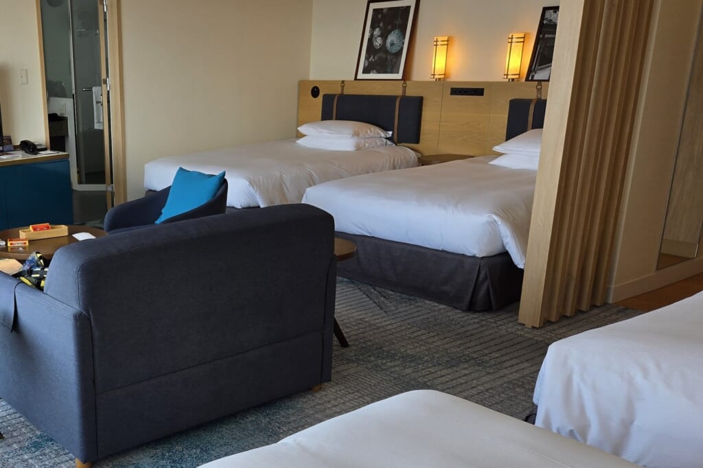 A family room at Hilton Fukuoka Sea Hawk with four single beds, a sofa and a small table.