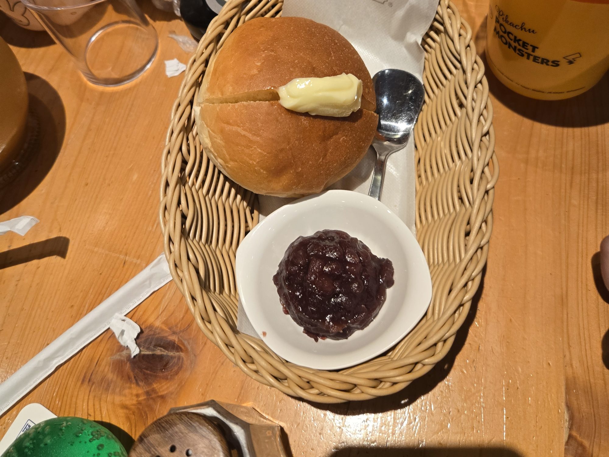 A Komeda Coffee morning set in a wicker basket: a round loaf roll with butter and a small dish of sweet red bean paste.