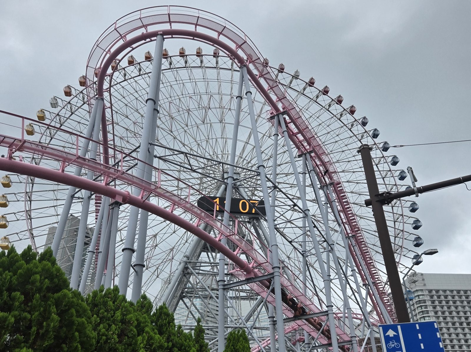 The Cosmo Clock 21 Ferris wheel and a roller coaster track at Yokohama Cosmo World under an overcast sky.